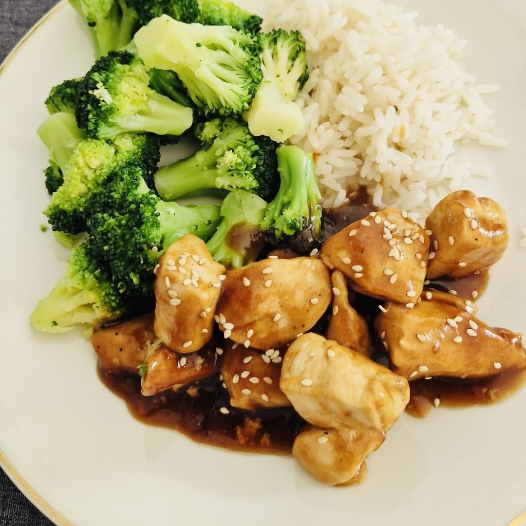 Gebratene Hähnchenstücke mit Brokkoli und Reis, garniert mit Sesam.